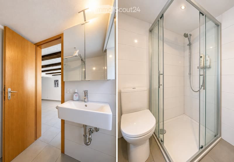 Modern bathroom with a white sink, mirror, and a glass-enclosed shower with a toilet. The space features white tiles and a wooden door.