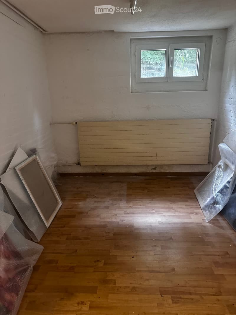 Empty room with wooden flooring, white walls, and a window with frosted glass. No furniture or equipment is present.