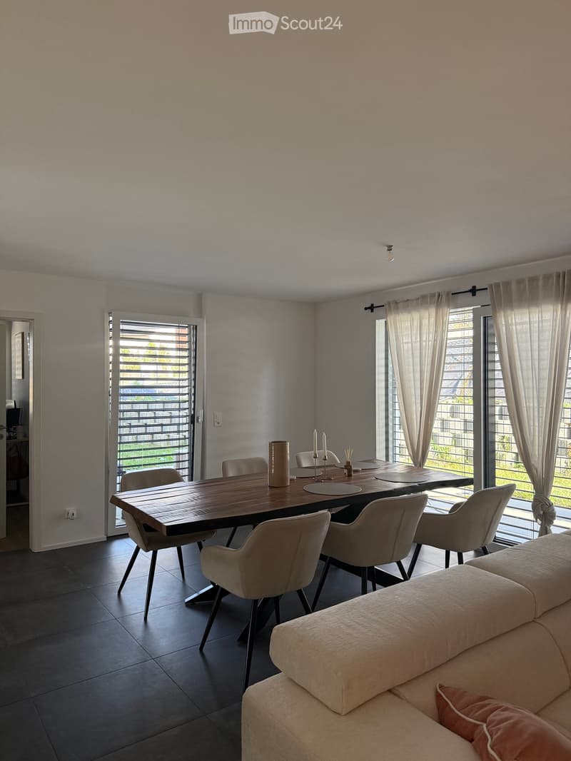 Modern living and dining area with a sofa, dining table, chairs, and decorative candles.