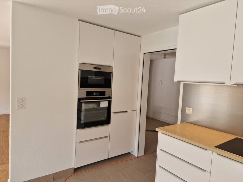 Modern kitchen with white cabinets, stainless steel oven, wooden countertop, and built-in stove.