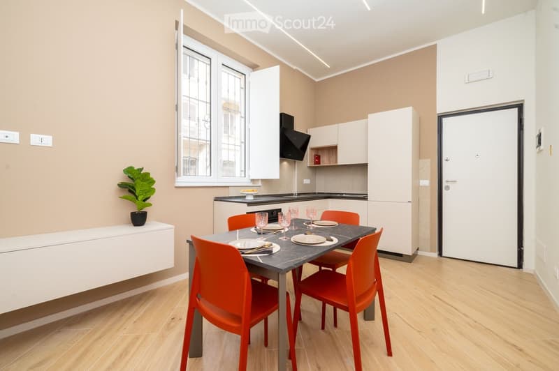 Modern dining area with a sleek black dining table, six orange chairs, white cabinets, and a potted plant on a white console table.