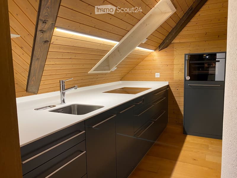 Modern kitchen with white countertops, dark grey cabinets, stainless steel sink and faucet, and built-in oven.