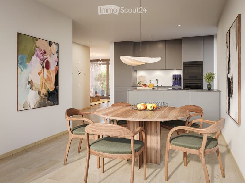 Modern dining area with a round wooden table and six chairs, adjacent to a sleek kitchen with grey cabinets, stainless steel appliances, and a pendant light. Artwork adorns the walls, and a fruit bowl sits on the table.