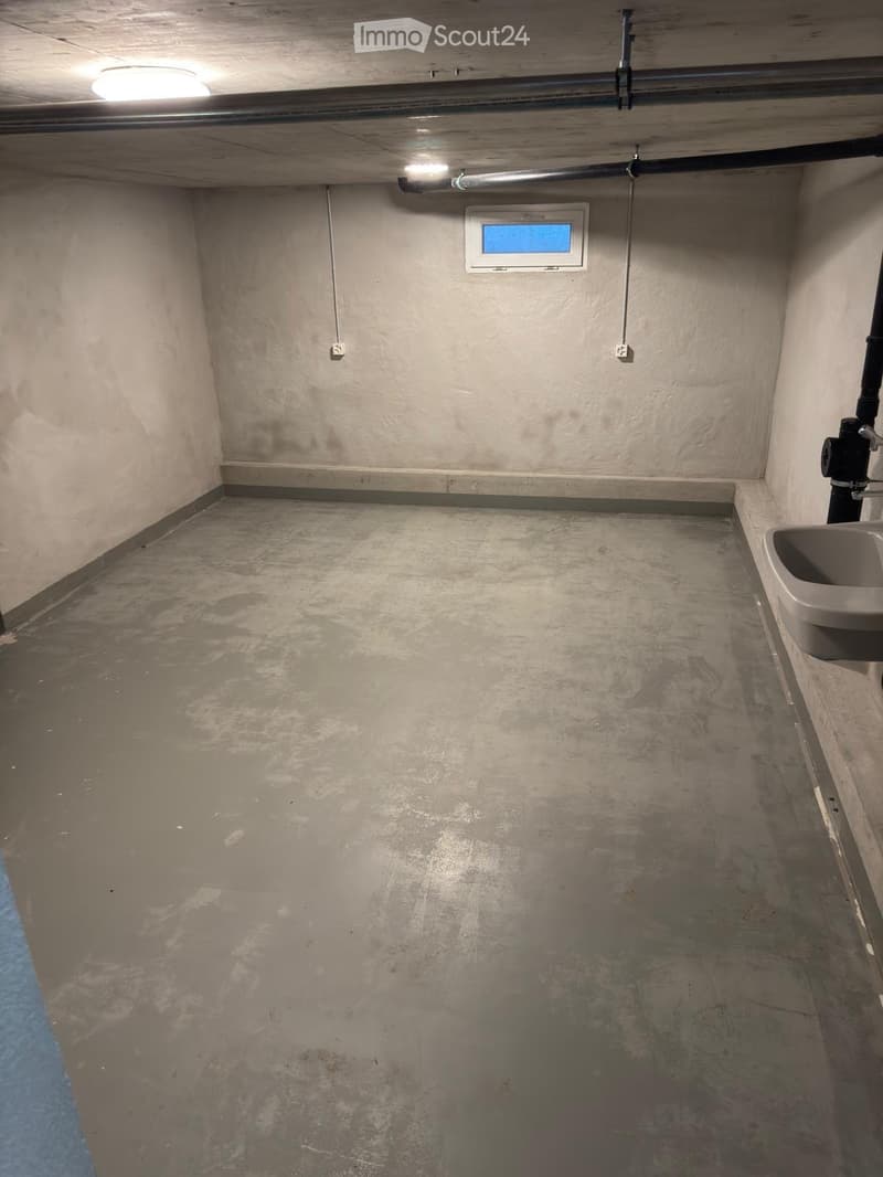 Empty room with concrete floor, beige walls, a small sink, and a window with blue tint.