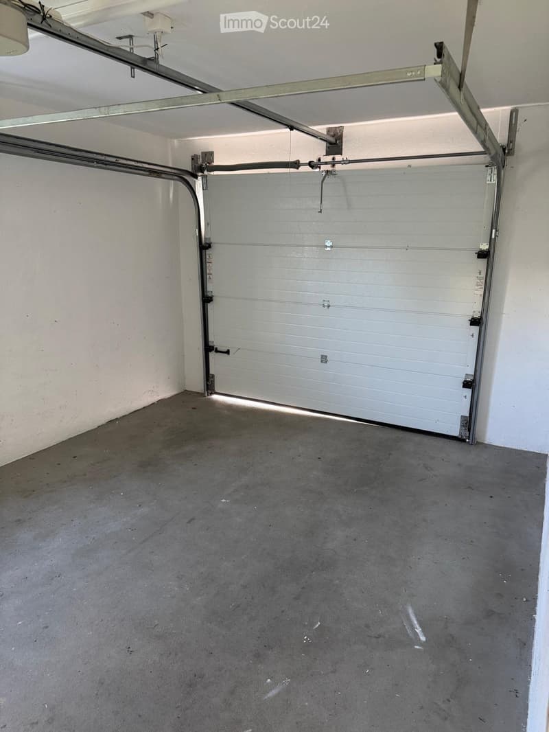 Empty garage with a closed garage door, concrete floor, and white walls.