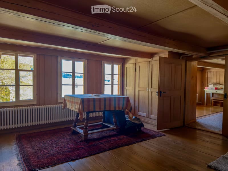 wooden floor, wooden walls, large windows, table with tablecloth, radiator, rug, open door