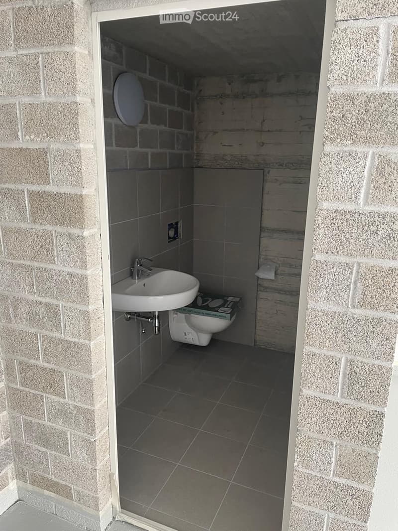 Small bathroom with a toilet, sink, and faucet, featuring tiled walls and floor.