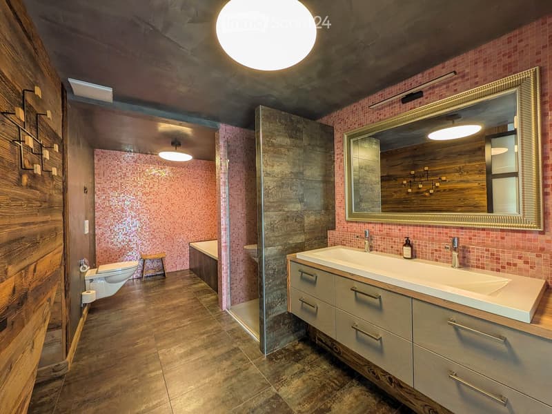 Modern bathroom with double sink vanity, large mirror, toilet, bathtub, and pink tiled shower area.