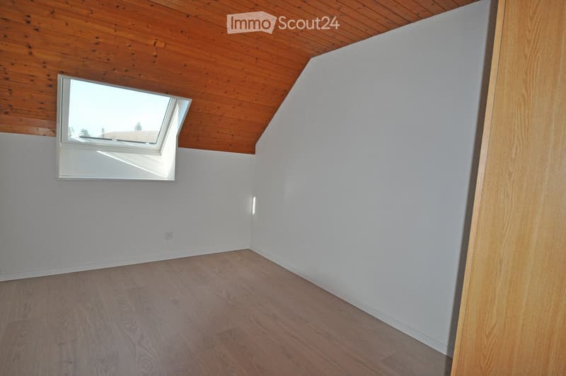 Empty room with wooden flooring, white walls, and a skylight window in the ceiling.
