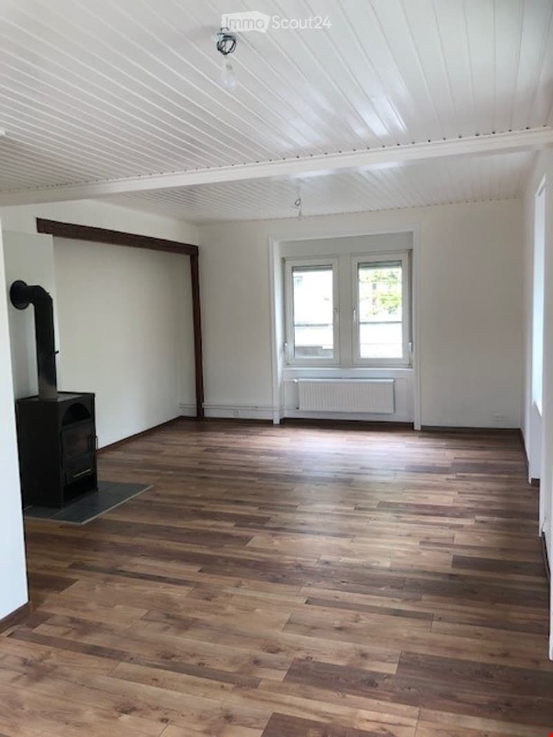 Empty room with wooden flooring, white walls, and a fireplace. No furniture or equipment present.