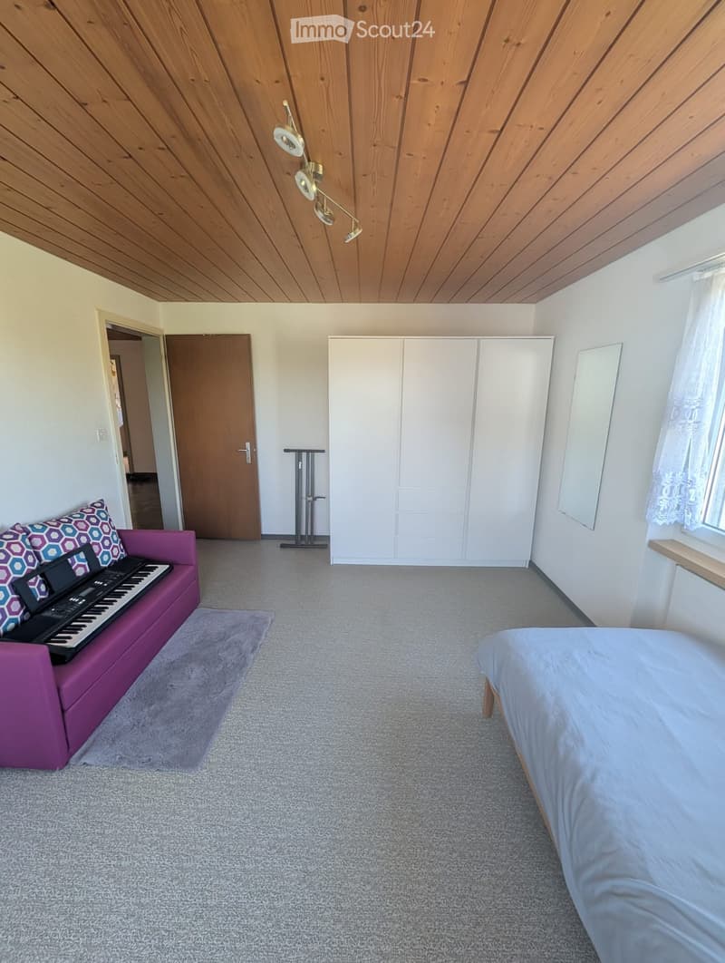 Bright bedroom with a purple sofa, piano, bed, white wardrobe, and a large mirror on the wall.