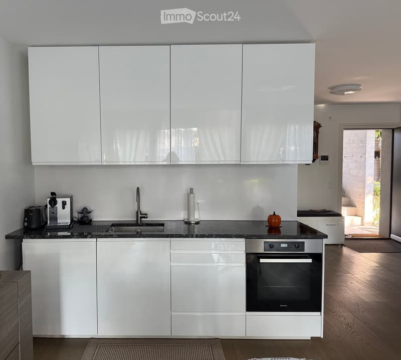 Modern kitchen with white cabinets, black countertops, stainless steel appliances, and a sink with a modern faucet.