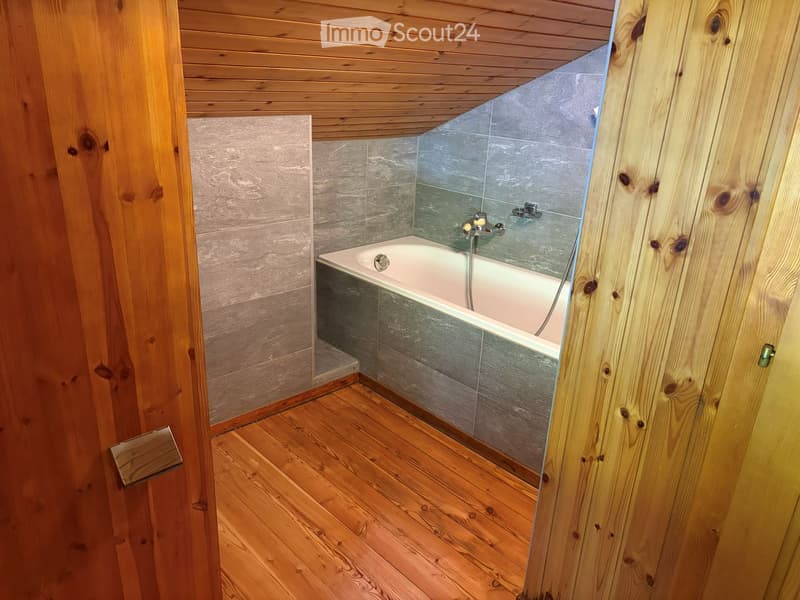 Bathroom with wooden walls and ceiling, a bathtub, and a modern faucet.