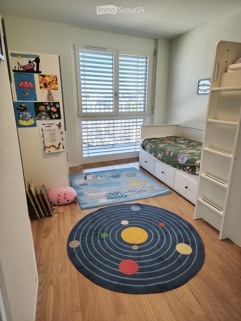 Cozy children's bedroom with a single bed, colorful rugs, books, and artwork on the walls.