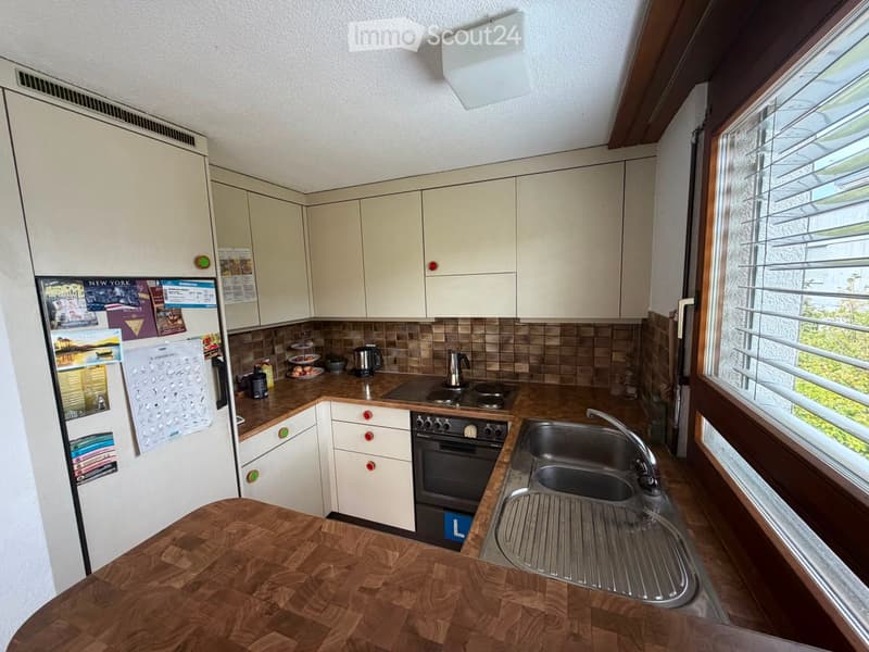 Modern kitchen with light-colored cabinets, a wooden countertop, a stainless steel sink, and various appliances including a refrigerator, oven, and coffee maker.