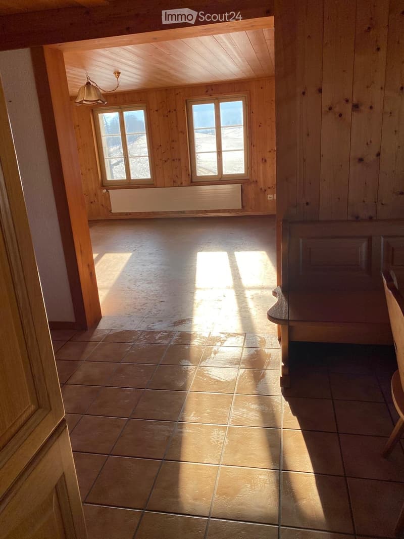 Empty room with wooden walls, tiled floor, and large windows letting in natural light. No furniture or equipment present.