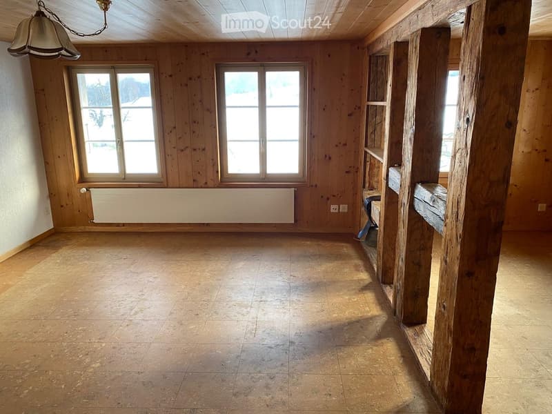 Empty room with wooden walls, tiled floor, large windows, and exposed wooden beams. No furniture or equipment present.