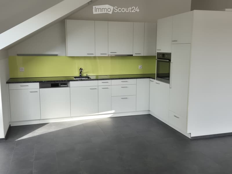 Modern kitchen with white cabinets, black countertops, and a green backsplash. Features a sink, oven, and dishwasher.
