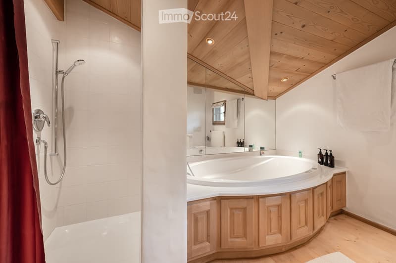 Modern bathroom with a wooden ceiling, a large bathtub, a shower area, and a mirror above the sink.