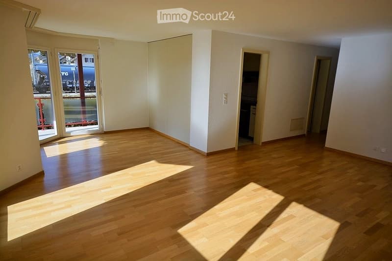 Empty room with wooden flooring, white walls, and large sliding glass doors leading to a balcony.