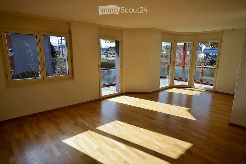Empty room with wooden flooring and large windows allowing natural light to fill the space. No furniture or equipment is present.