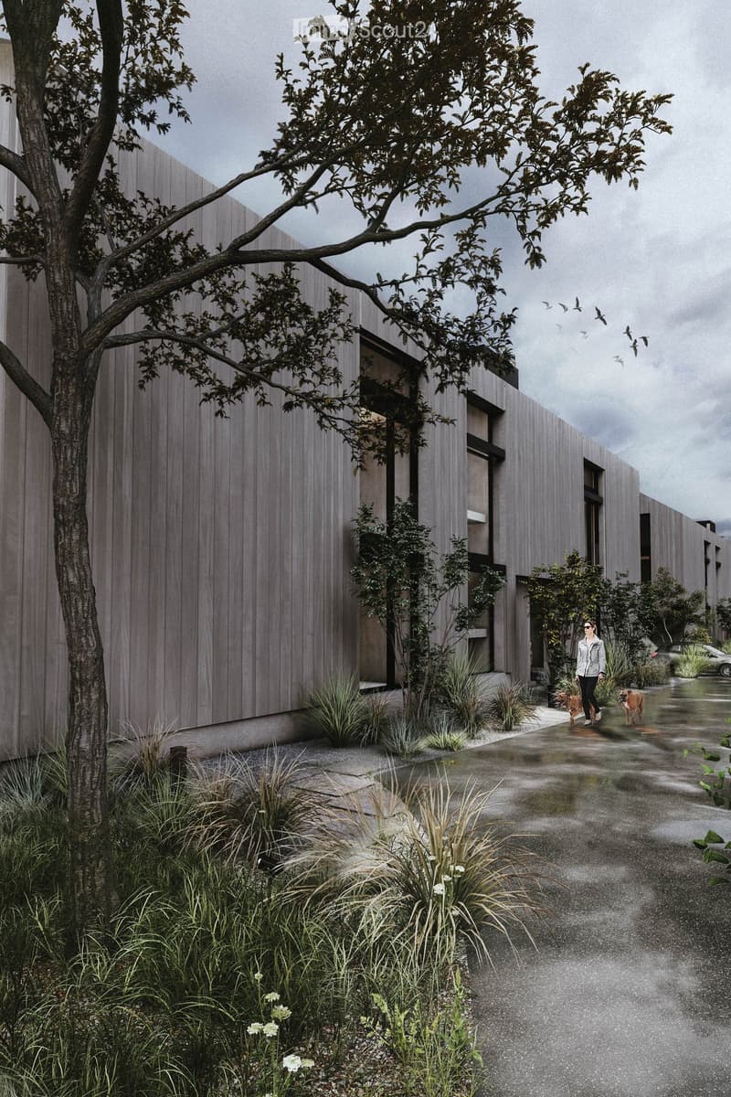 A modern multi-story building with a gray exterior, surrounded by trees and landscaping. There are balconies or terraces visible on the building. A person and their dog are walking along the path in the foreground.