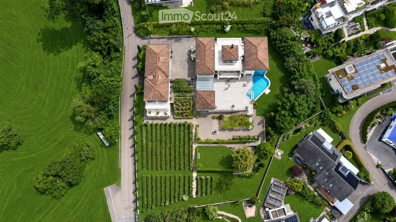 Aerial view of a large residential property with a swimming pool, garden, and multiple buildings.