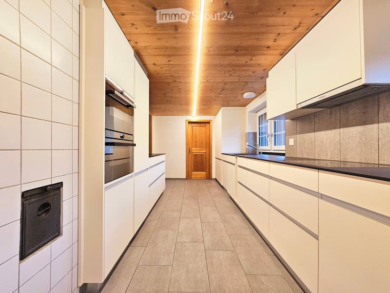 Modern kitchen with white cabinets, stainless steel appliances, and a wooden ceiling.