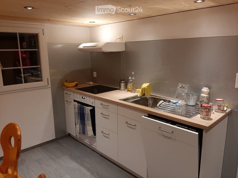 Modern kitchen with white cabinets, stainless steel sink, built-in oven, and various kitchen items on the counter.