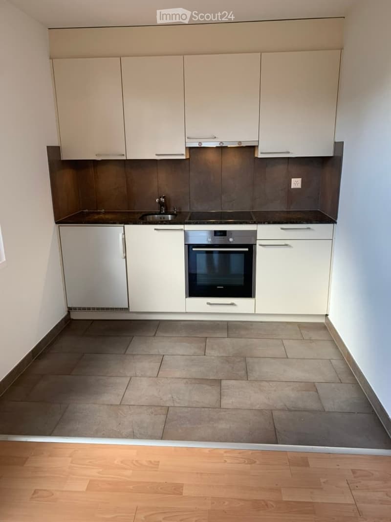 Modern kitchen with white cabinets, stainless steel appliances, and tiled floor.