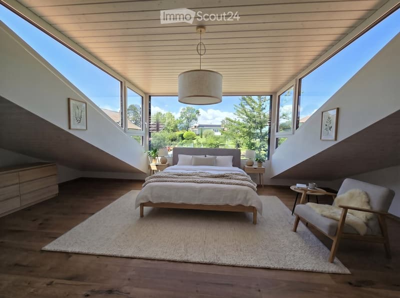 Bright, airy bedroom with wooden floors, large windows, a bed with white bedding, a wooden chair with a fur throw, side tables, and a hanging pendant light.