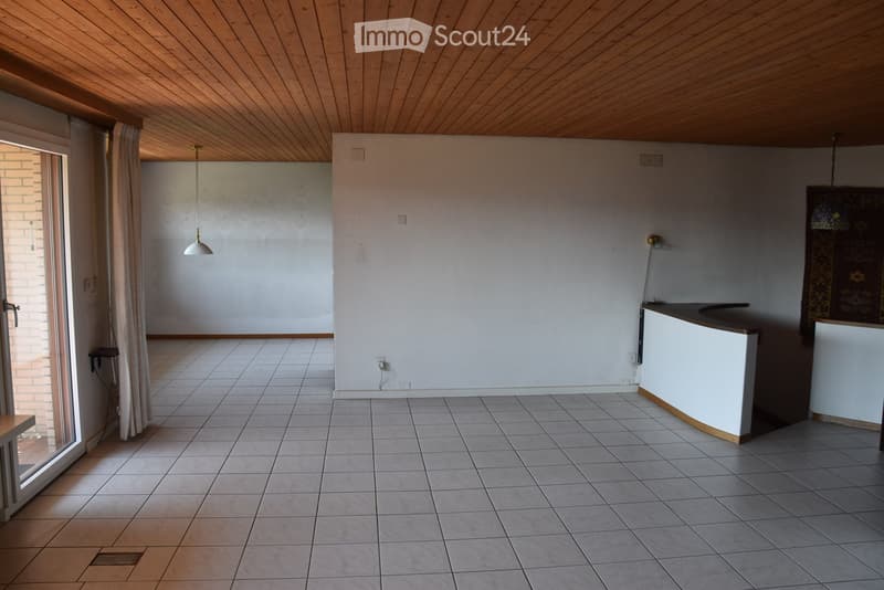 Empty room with tiled floor, white walls, wooden ceiling, and a small counter. No furniture or equipment present.