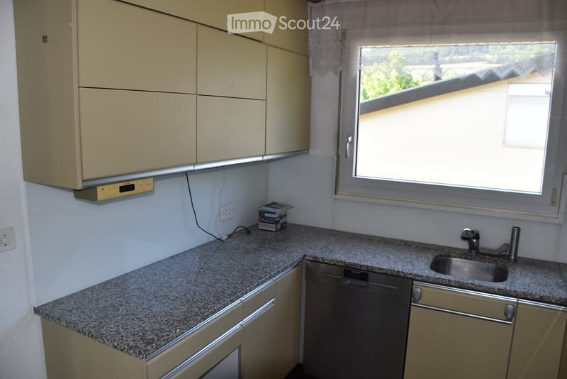 Modern kitchen with granite countertop, stainless steel sink and faucet, built-in dishwasher, and light-colored cabinets.