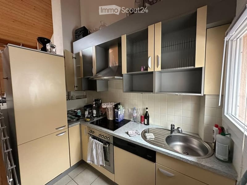 Kitchen with beige cabinetry, stainless steel appliances, a sink with a faucet, a countertop, a window, and an extractor hood over the stove.