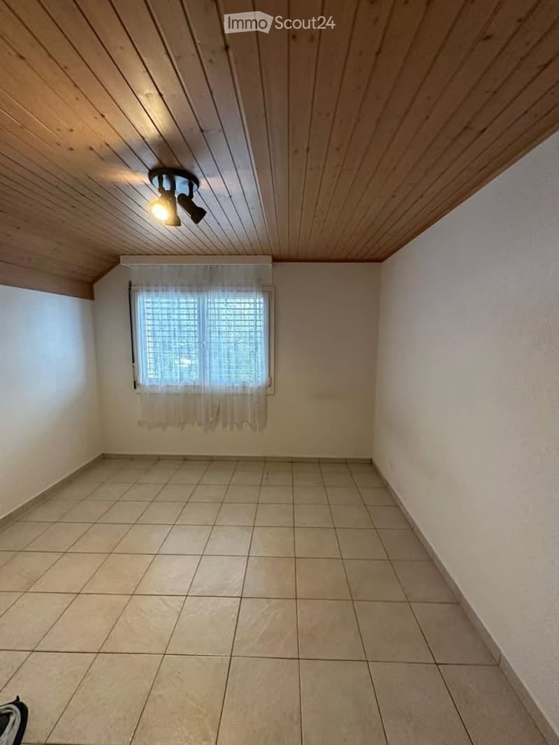empty room with light wooden ceiling, tiled floor, white walls, and a window with white curtains