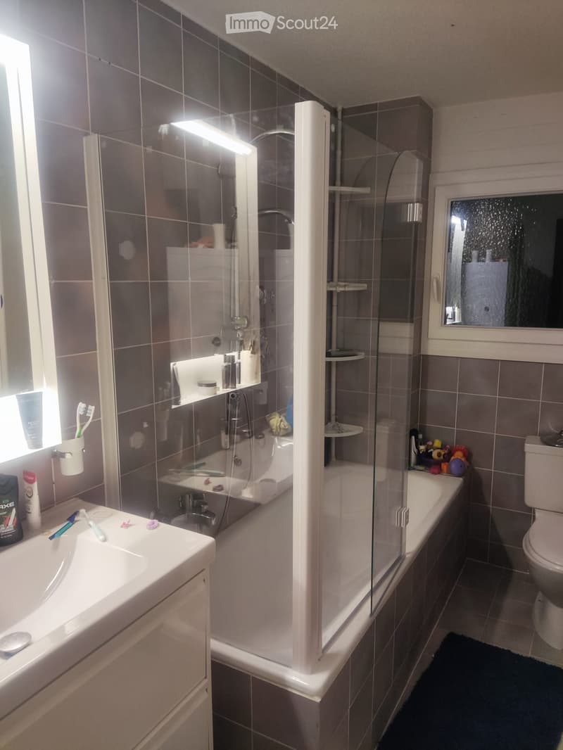 tiled walls, white sink, vanity, glass shower enclosure, white toilet, shelves, mirror