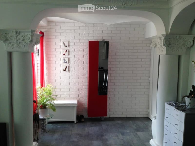 Furnished Room. A modern hallway with white brick walls, decorative columns, a small table with a plant, and a cabinet with drawers.