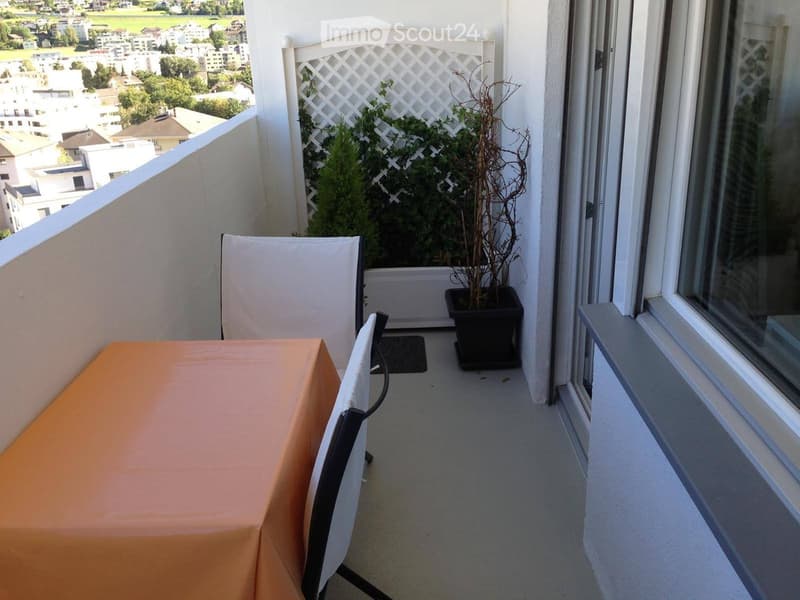 Balcony / Terrace. Balcony with a small table, chairs, and a potted plant, overlooking a cityscape.