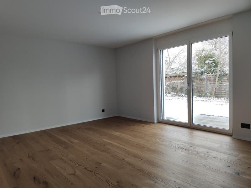 Empty room with wooden flooring and large sliding glass doors leading to a snowy outdoor area.