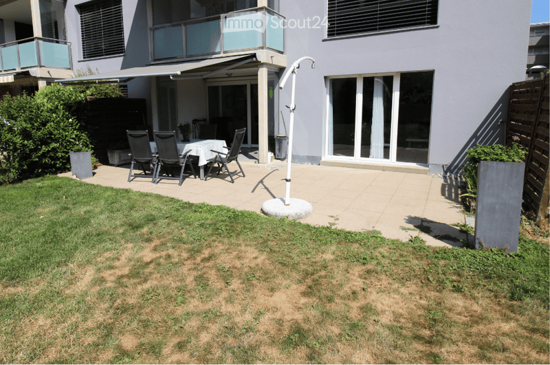 Garden area with a patio, outdoor dining set, and a covered balcony area connected to the house.