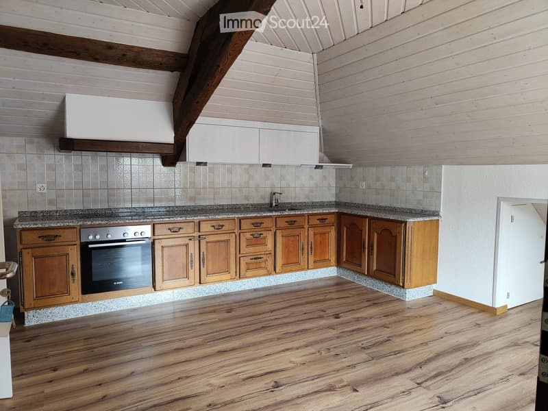 Modern kitchen with wooden cabinets, granite countertops, and a built-in oven. Exposed wooden beams on the ceiling and tiled backsplash.