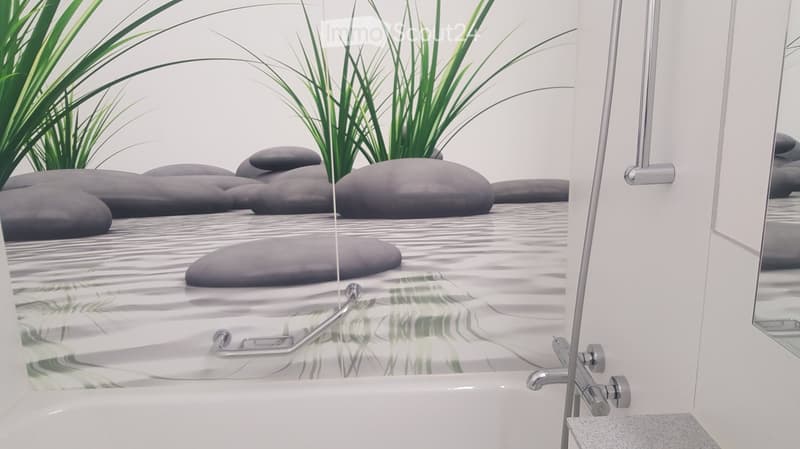 A bathroom with a bathtub, silver shower fixture, and a wall mural of rocks and water