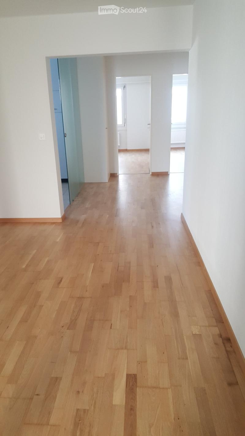 Empty hallway with white walls, wooden floor, large window