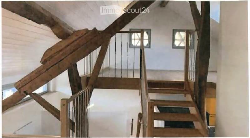 Wooden staircase with metal railing, white walls, and small square windows on the landing.