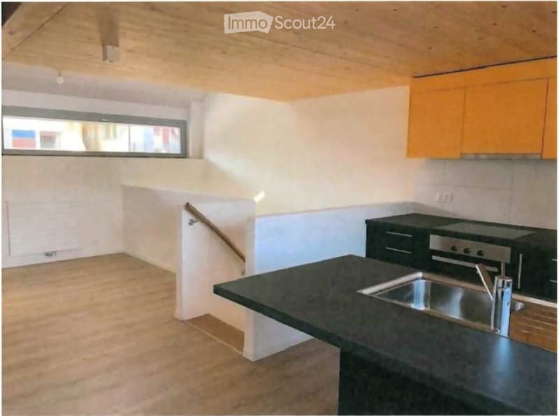 Modern kitchen with black countertops, stainless steel sink, stove, and orange cabinets.