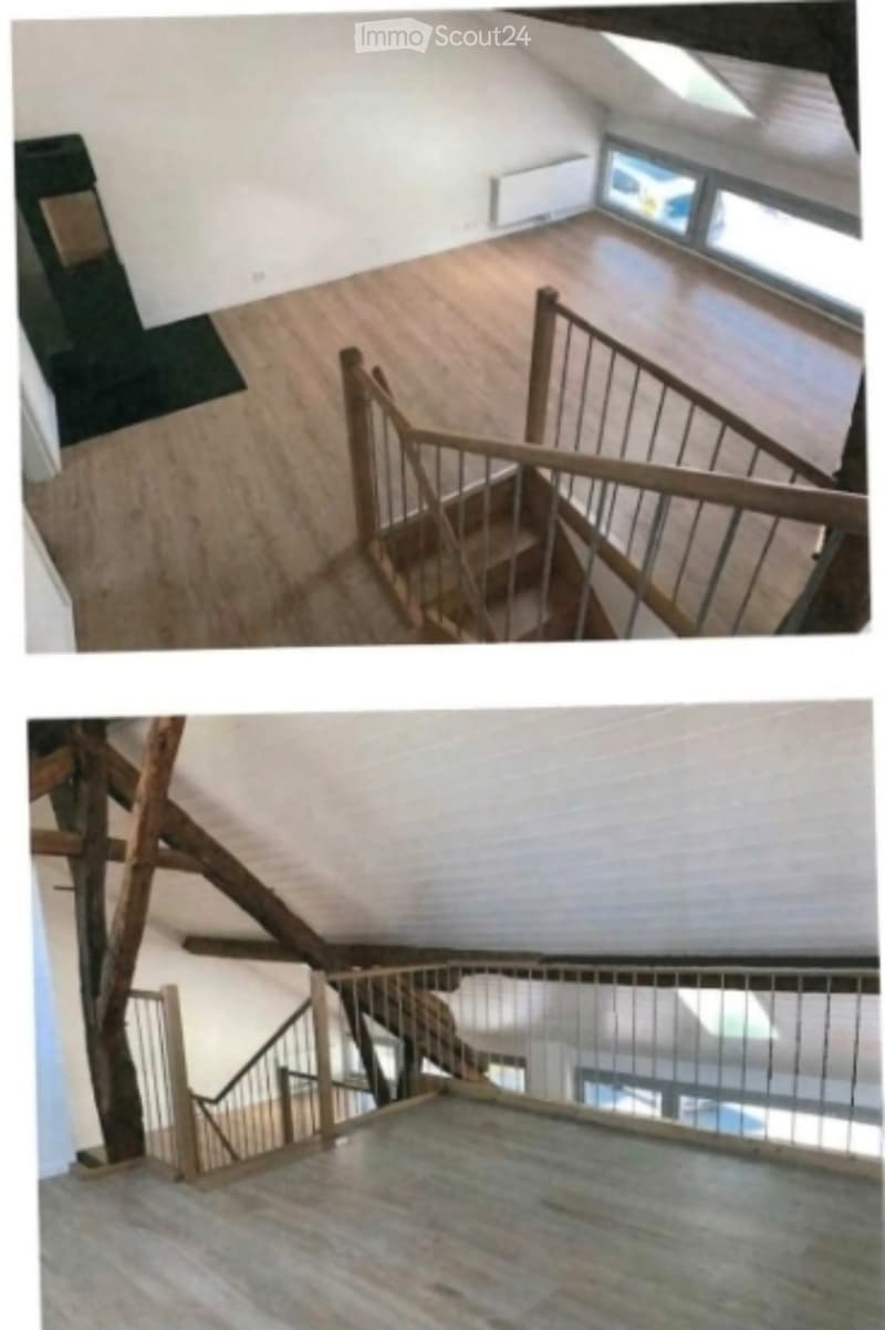 Spacious hallway with wooden flooring, white walls, and large windows allowing natural light. Features a wooden staircase with metal railings leading to an upper level.