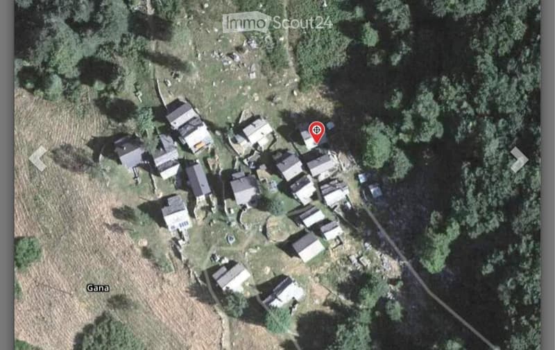 Aerial view of a rural village with multiple small houses and structures surrounded by greenery and trees.