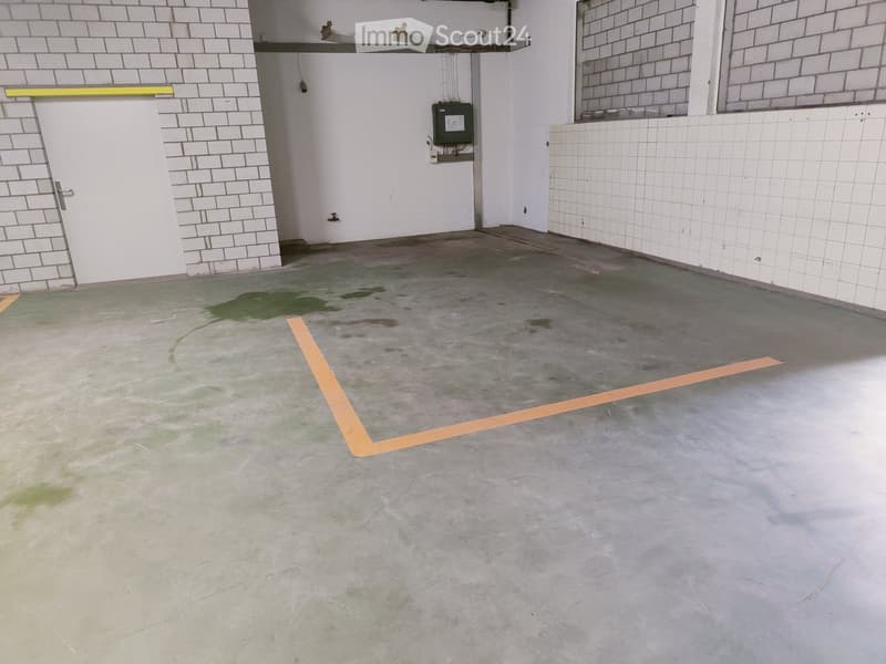 Empty room with concrete floor, white tiled walls, and a single door. No furniture or equipment present.