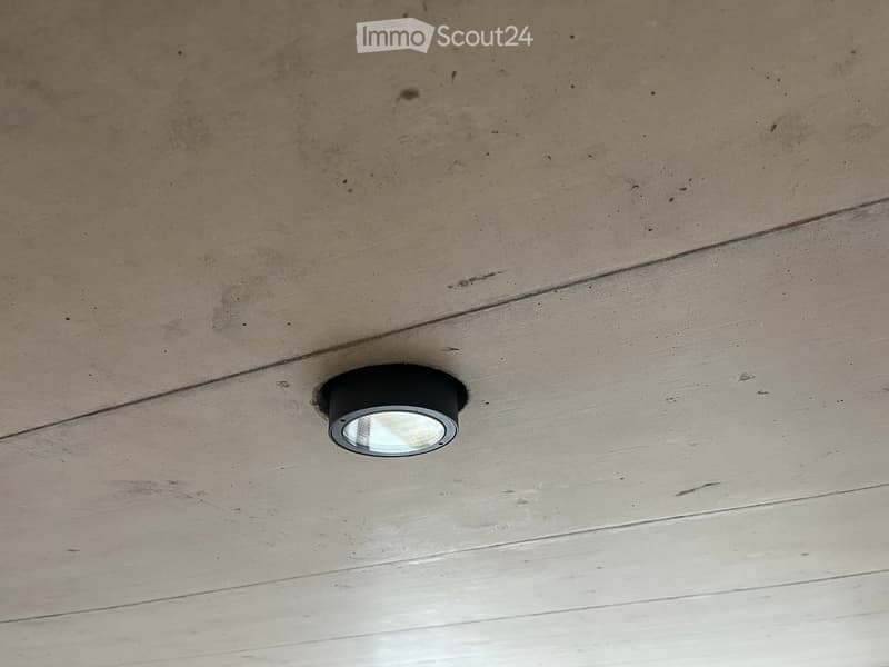 An unfurnished room with a wooden ceiling and a single recessed light fixture.