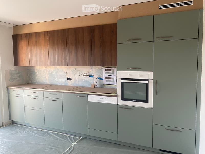 Modern kitchen with grey and brown cabinets, stainless steel appliances, and a tiled backsplash.